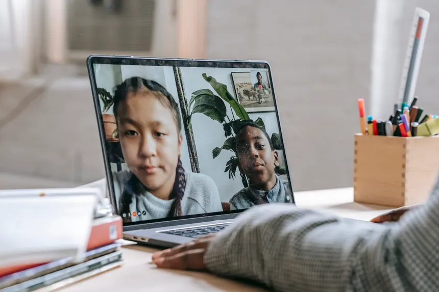 Side view of crop anonymous African American female talking with children online on laptop