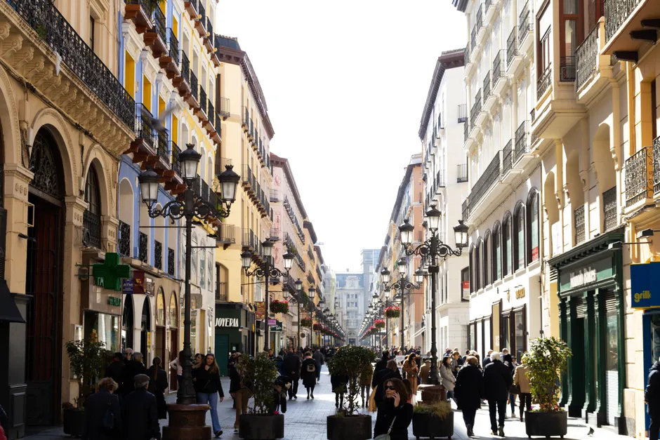 Crowded pedestrian street in Zaragoza, Spain, showcasing vibrant city life and architecture.