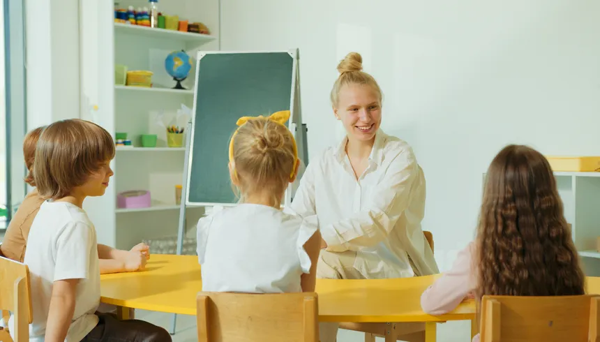 Teacher engaging with preschool children in a colorful classroom setting.