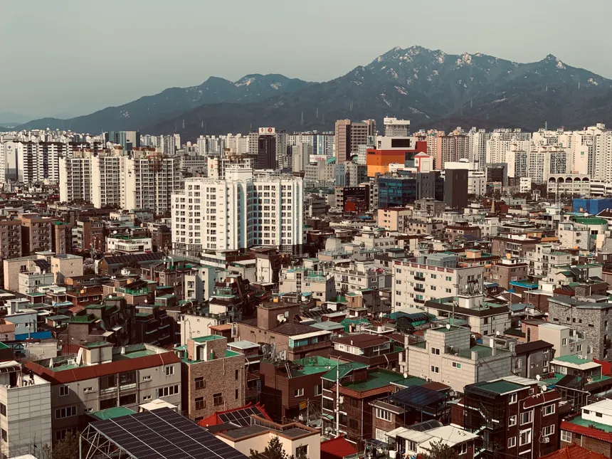 Aerial cityscape of Seoul with mountains, showcasing the urban density and architecture.