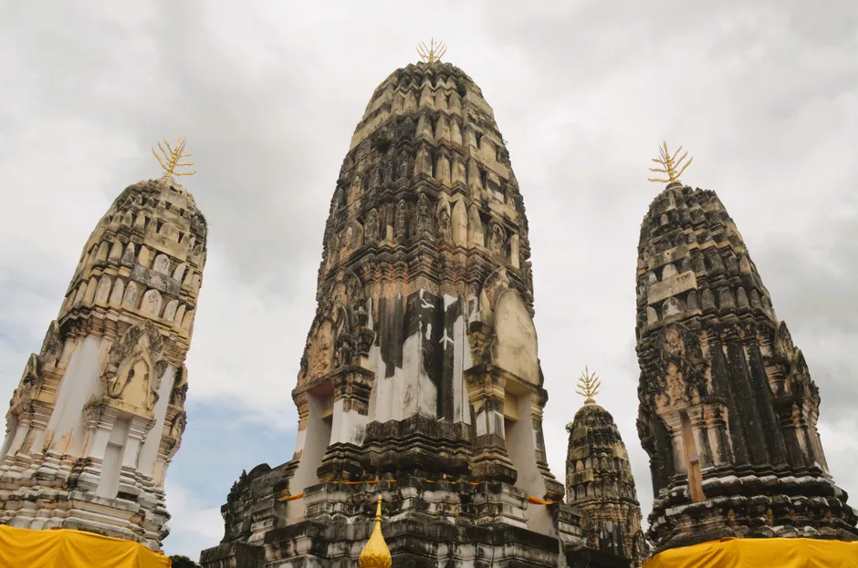 Explore the majestic ancient stone temples at Wat Phra Si Sanphet under a cloudy sky.