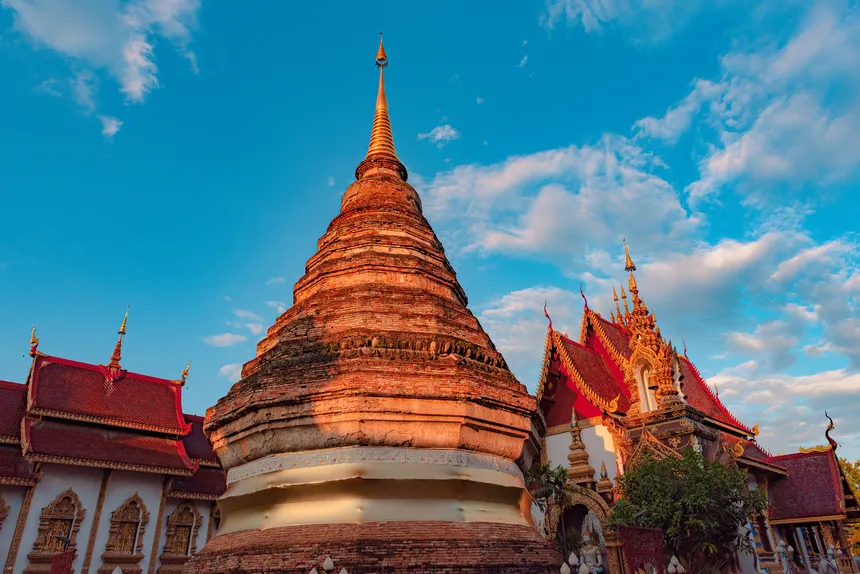 Stunning view of a traditional Buddhist temple against a bright blue sky in Chiang Mai, Thailand.