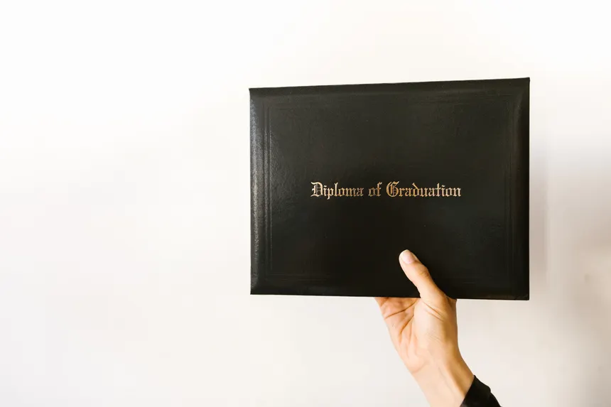 Close-up of a hand holding a graduation diploma with elegant typography.